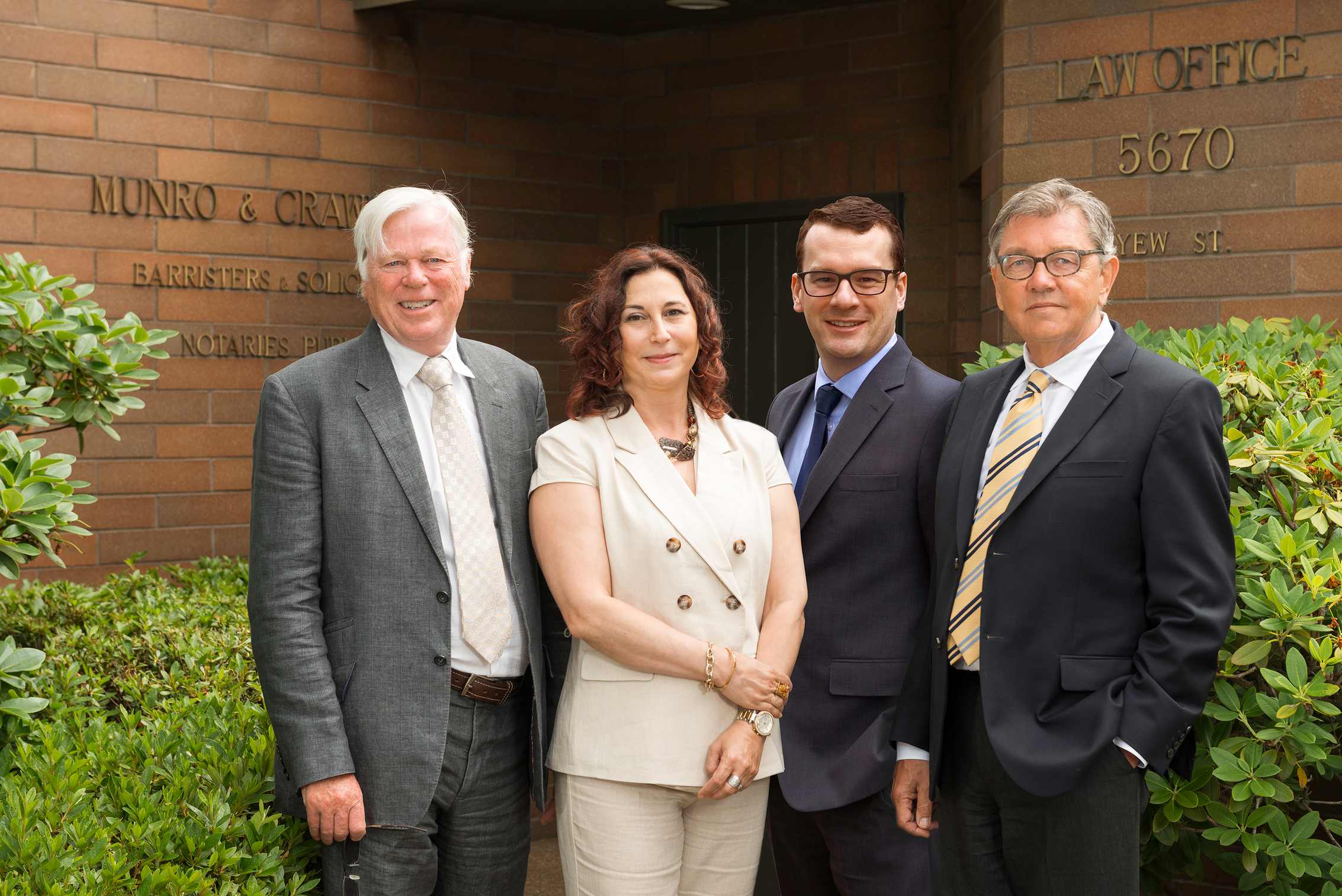 Munro & Crawford's core legal team pictured in front of their office at 5670 Yew Street in Vancouver, BC. From left to right: Peter Crawford, Katarina Tagliafero, Andrew Beesley, and Ronald Argue.