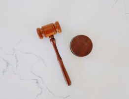 Wooden gavel lying on a white marble surface.