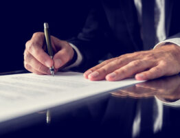 Hands signing a legal document.