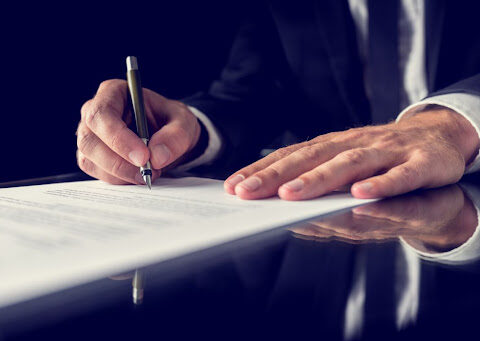 Hands signing a legal document.