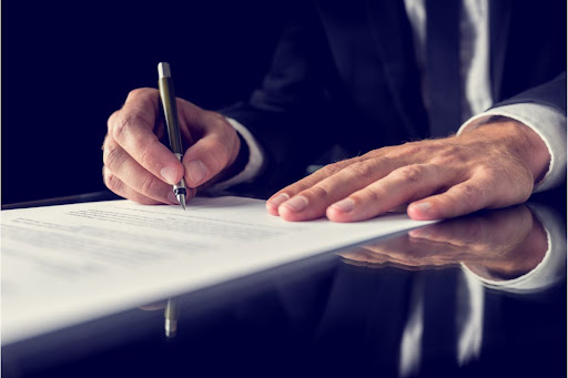 Hands signing a legal document.