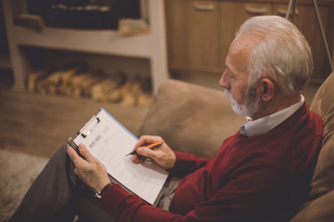 An elder man filling out will paperwork.